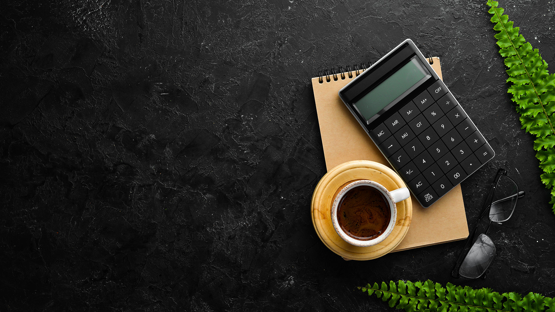 calculator, notepad, and coffee sitting on a desk
